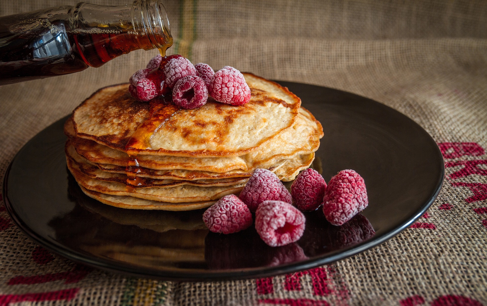 Pancakes mit Himbeeren und Ahornsirup.