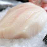 Ein frisches Heilbuttfilet liegt auf zerstoßenem Eis an einer Fischtheke