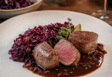 Wie schmeckt Reh? Rosa gebratene Rehmedaillons mit Rotkohl und Sauce auf einem Teller angerichtet
