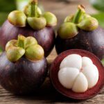 Aufgeschnittene Mangostan-Frucht mit weißem Fruchtfleisch auf Holztisch