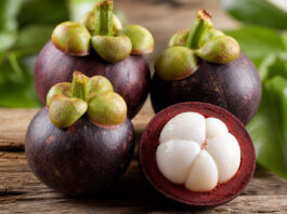 Aufgeschnittene Mangostan-Frucht mit weißem Fruchtfleisch auf Holztisch