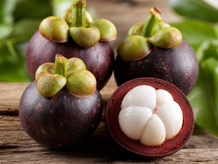 Aufgeschnittene Mangostan-Frucht mit weißem Fruchtfleisch auf Holztisch