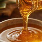 Goldener Agavendicksaft wird zähflüssig aus einem Glas in eine Schale gegossen