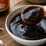 Eine Schale dunkle, glänzende Austernsauce mit Löffel in Nahaufnahme