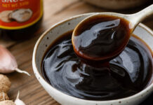 Wie schmeckt Austernsauce? Eine Schale dunkle, glänzende Austernsauce mit Löffel in Nahaufnahme
