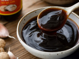 Wie schmeckt Austernsauce? Eine Schale dunkle, glänzende Austernsauce mit Löffel in Nahaufnahme