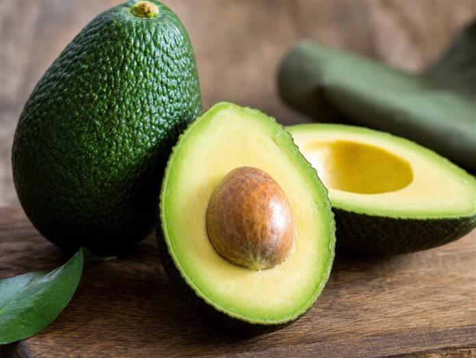 Ganze und aufgeschnittene Avocado mit Kern auf Holzbrett