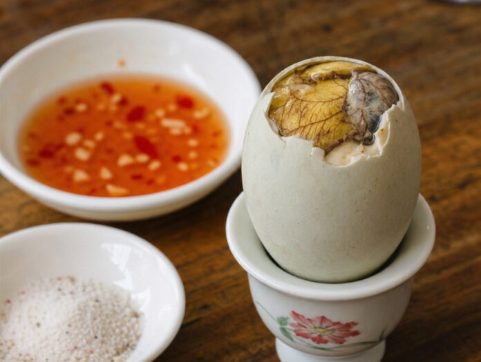 Balut philippinisches Straßenessen Gekochtes Balut-Ei im Eierbecher mit Salz und Chili-Dip serviert