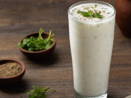 Ein Glas gekühlte Buttermilch mit Kondenswasser auf einem Holztisch