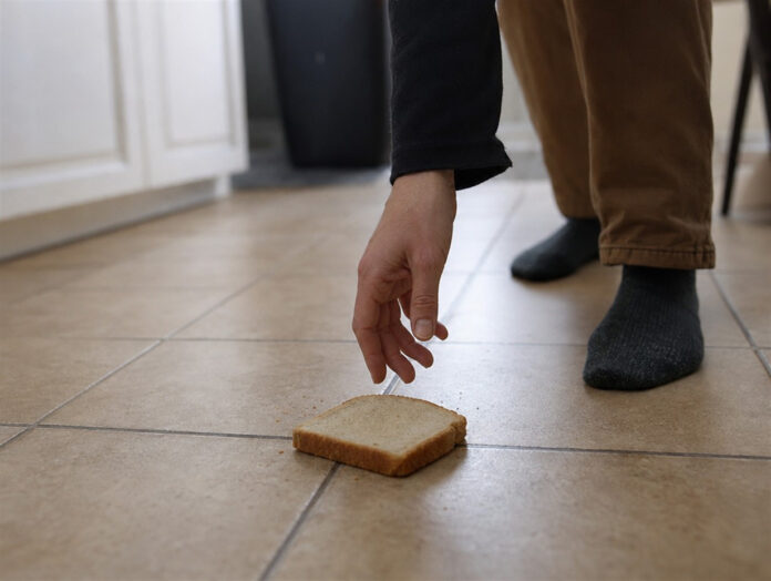 Ein Stück Brot fällt auf den Küchenboden