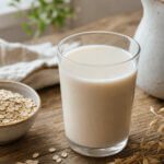 Ein Glas Hafermilch neben Haferflocken
