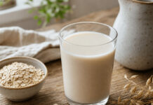Wie schmeckt Hafermilch? Ein Glas Hafermilch neben Haferflocken