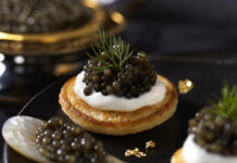 Wie schmeckt Kaviar? Kaviar auf Blini mit Crème fraîche, serviert mit einem Perlmuttlöffel