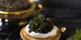 Wie schmeckt Kaviar? Kaviar auf Blini mit Crème fraîche, serviert mit einem Perlmuttlöffel