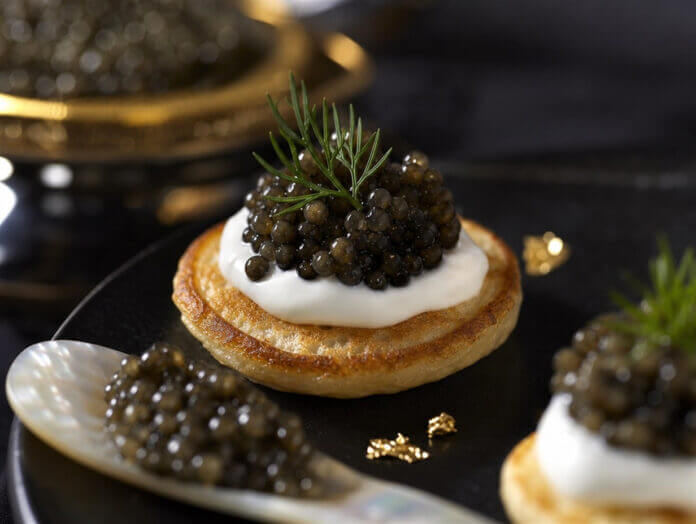 Kaviar auf Blini mit Perlmuttlöffel Kaviar auf Blini mit Crème fraîche, serviert mit einem Perlmuttlöffel
