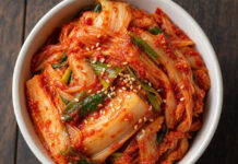 Wie schmeckt Kimchi? Schüssel mit fermentiertem, leuchtend rotem Kimchi aus Chinakohl