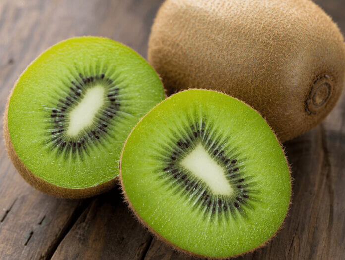 Wie schmeckt Kiwi – Titelbild Aufgeschnittene Kiwi mit saftig-grünem Fruchtfleisch und schwarzen Kernen neben einer ganzen Kiwi