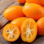 Ganze und halbierte Kumquats auf Holzuntergrund
