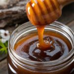 Glas mit dunklem Manuka-Honig und Holzlöffel