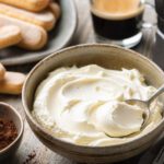 Cremiger Mascarpone in einer Schale mit Löffel neben Tiramisu-Zutaten