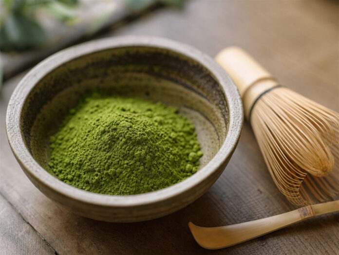 Matcha-Pulver mit Bambusbesen Schale mit grünem Matcha-Pulver und Bambusbesen auf Holztisch