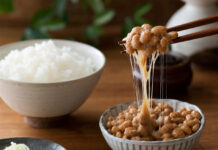 Wie schmeckt Natto? Eine Schale Natto mit klebrigen Fäden, angehoben mit Stäbchen