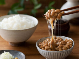 Eine Schale Natto mit klebrigen Fäden, angehoben mit Stäbchen
