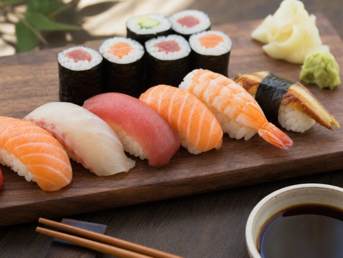 Nigiri und Maki Sushi auf dunklem Holzbrett mit Stäbchen und Ingwer