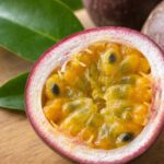 Halbierte Passionsfrucht mit gelb-orangem, gallertartigem Fruchtfleisch und schwarzen Kernen