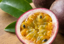 Wie schmeckt Passionsfrucht? Halbierte Passionsfrucht mit gelb-orangem, gallertartigem Fruchtfleisch und schwarzen Kernen