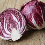 Ein halbierter Radicchio-Kopf mit rot-weißen Blättern neben einem ganzen Radicchio