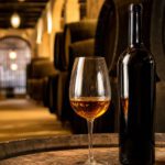 Ein Glas bernsteinfarbener Sherry neben der Flasche in einer spanischen Bodega