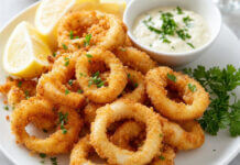 Wie schmeckt Tintenfisch (Calamari)? Frittierte Tintenfischringe (Calamari) serviert mit Zitronenspalten und Aioli