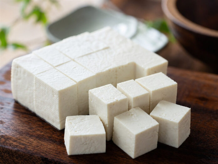 Tofu in Würfel geschnitten Frischer Tofu wird auf einem Holzbrett in Würfel geschnitten