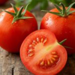 Halbierte reife Tomate mit sichtbaren Kernen neben ganzen Tomaten