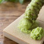 Frisches Wasabi-Rhizom wird auf einer traditionellen Reibe zu grüner Paste gerieben