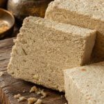 Aufgeschnittene Halva mit sichtbarer krümeliger Sesamstruktur auf Holzuntergrund