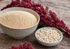 Wie schmeckt Amaranth? Große Schale mit winzigen hellen Amaranthkörnern neben einer kleinen Schale gepopptem Amaranth und roten Amaranthblütenrispen