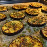 Goldbraun gegrillte Auberginenscheiben mit Olivenöl und Kräutern auf einem Backblech