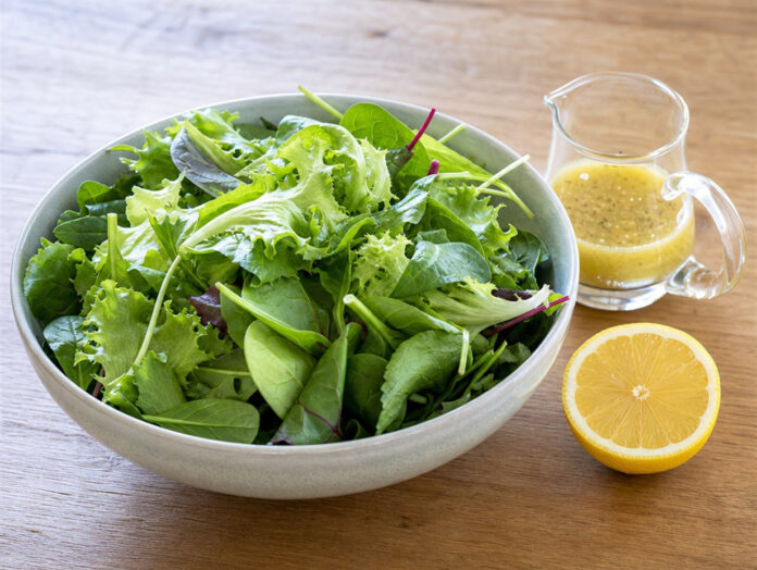 Schüssel mit gemischtem Blattsalat und Dressing Große Schüssel gemischter Blattsalat neben einer Kanne Dressing und einer halben Zitrone