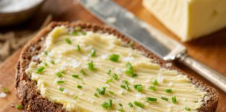 Tag des Deutschen Butterbrotes: Termin, Butterarten und Zahlen Dicke Scheibe dunkles Roggenbrot mit kalter Butter bestrichen, mit grobem Salz und Schnittlauch bestreut