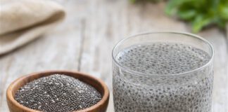 Wie schmecken Chiasamen? Holzschale mit trockenen dunklen Chiasamen neben einem Glas Wasser, in dem die Samen zu durchsichtigem Gel aufgequollen sind