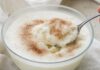 Wie schmeckt Dickmilch? Glasschale mit dicker weißer Sauermilch, ein Löffel hebt eine Portion heraus, bestreut mit Zucker und Zimt