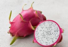 Warum schmeckt Drachenfrucht nach nichts? Ganze pinke Drachenfrucht mit grünen Schuppen neben einer aufgeschnittenen Hälfte mit weißem Fruchtfleisch
