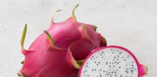 Warum schmeckt Drachenfrucht nach nichts? Ganze pinke Drachenfrucht mit grünen Schuppen neben einer aufgeschnittenen Hälfte mit weißem Fruchtfleisch