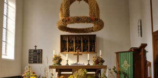 Erntedankfest: Herkunft, Bräuche und was auf den Tisch kommt Mit Getreidegarben, Kürbissen, Äpfeln und Brot geschmückter Erntedankaltar mit geflochtener Erntekrone in einer Kirche
