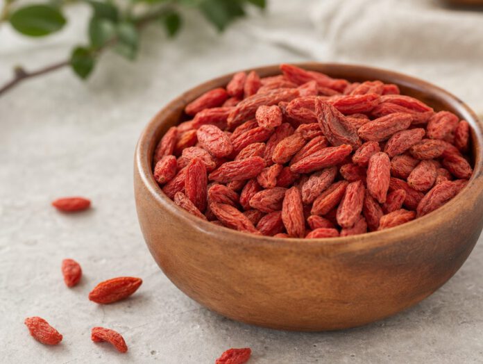 Getrocknete orangerote Goji-Beeren mit runzliger Oberfläche in einer Holzschale auf hellem Stein