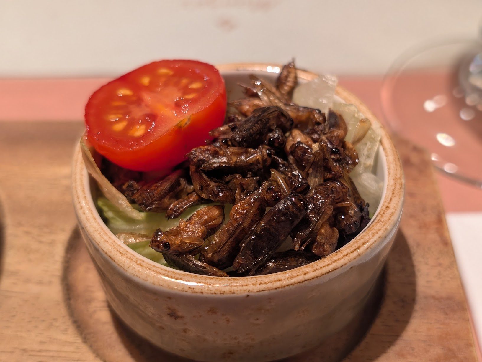 Geröstete ganze Grillen in einem Schälchen mit Tomate und Salat