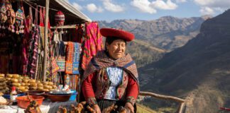 Meerschweinchen essen: Wie schmeckt Cuy in Peru? Marktstand in Peru mit Spießen über Holzkohle vor bunten Textilien und Bergkulisse