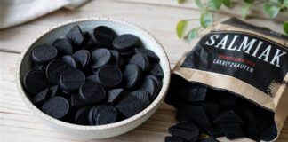 Salmiakki: Wie schmeckt Finnlands Salzlakritz? Tiefschwarze Lakritzpastillen und Rauten in einer Schale auf hellem Holz